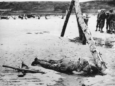 Crossed rifles beside fallen US soldier on D-Day Omaha Beach