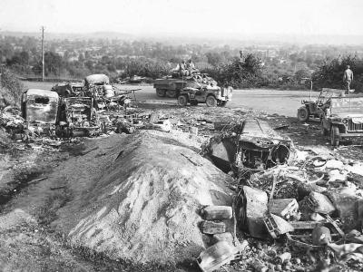 M8 and Jeep passing wrecked German vehicles in Avranches