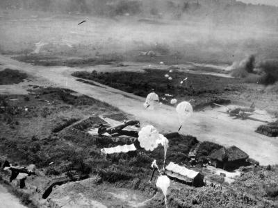 Parachute bombs are dropping from low-flying American planes on revetments protecting dispersed G4M bombers