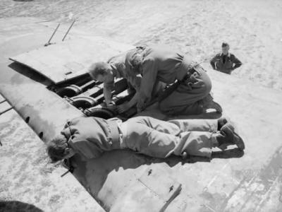 Armourers of No. 89 Squadron RAF installing a 0.303 Browning machine gun in the wing of a Bristol Beaufighter Mk VIF at Castel Benito Libya