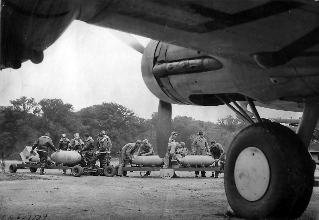 Pilot chalks message on bomb as crewmen load B-17, England 1942