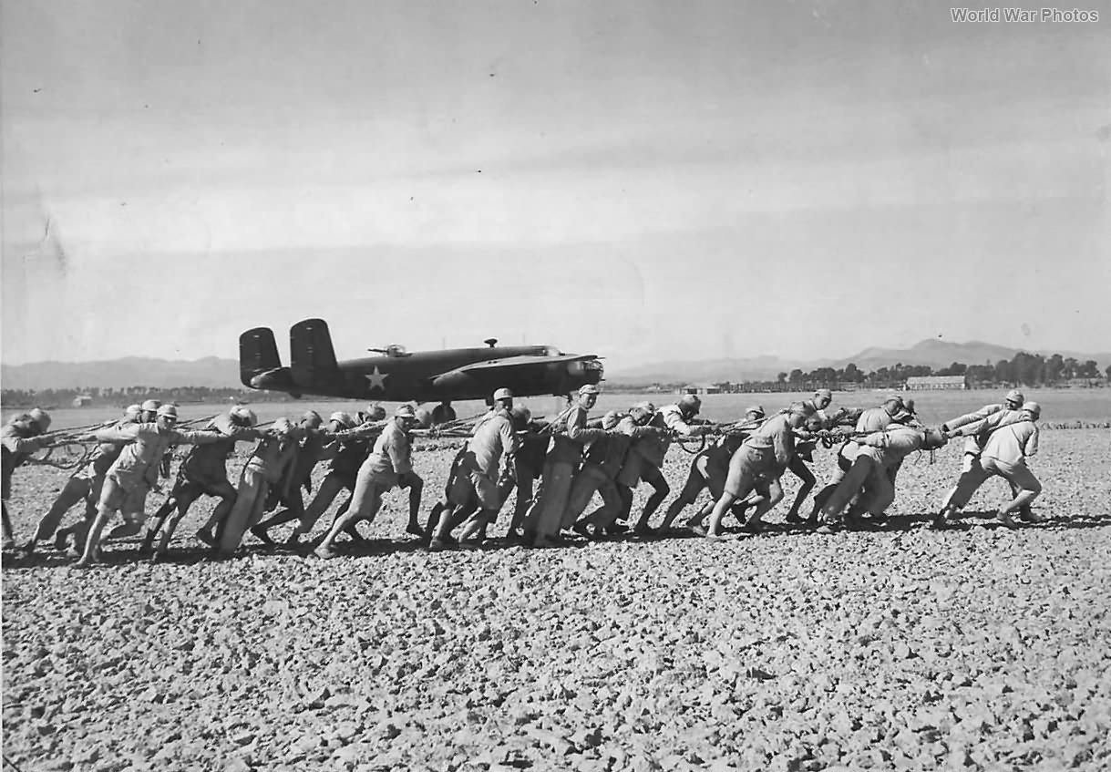 Chinese Troops pull roller past B-25 to smooth airstrip in China 1943