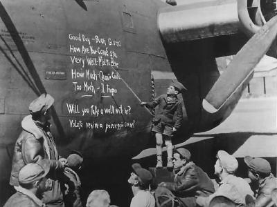 Small boy uses the side of a B-24 as a blackboard to give US airmen a lesson in Italian 44
