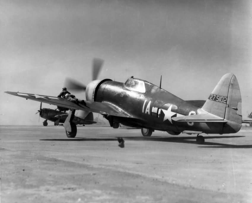 Ground crew man of the 358th FG guides a taxying P-47 Thunderbolt 42-75102