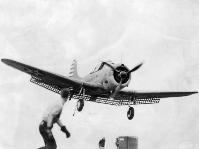 Crewmen aid SBD Dauntless landing on carrier