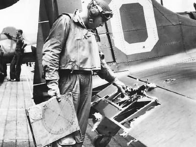 Lt. James K. Brothers of VB-9 inspects damage to his SBD-5 white 10 after returning safely to the aircraft carrier USS Essex following raid on Tarawa 1943