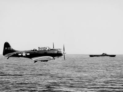 SBD-5 Dauntless code M23 makes a low pass over the flight deck of the carrier Lexington (CV-16) to make a message drop on April 16, 1944