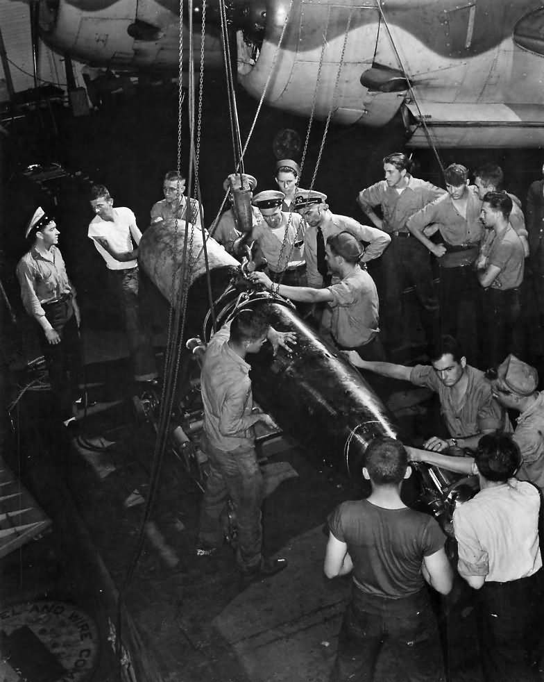 Crew loading torpedo on TBF aboard aircraft carrier 1943