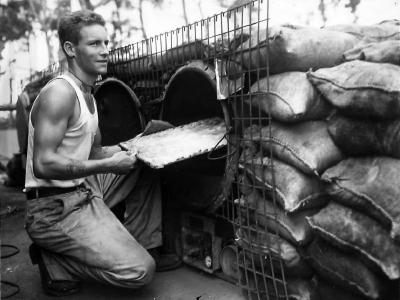 Marine cook baking in makeshift oven on Cape Gloucester