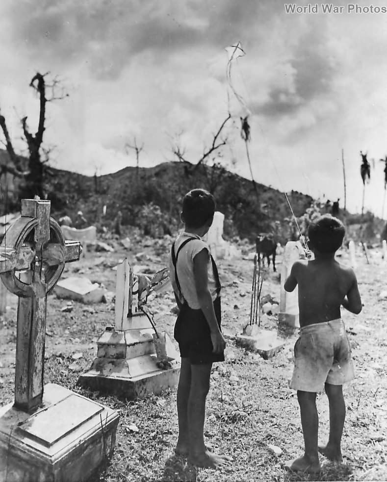 Chamorro boys fly kite in wrecked Pigo Cemetery on Guam