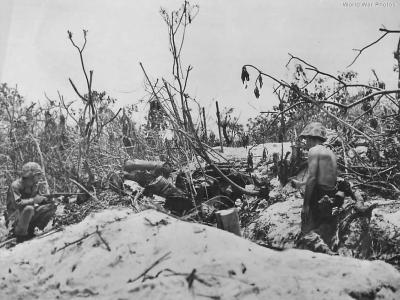 Marine with a carbine covers the entrance to a Japanese pillbox