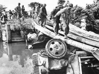 U.S. Troops use wrecked trucks to build bridge on Luzon