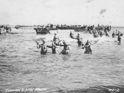 US Marines wade ashore on Tinian from landing barges, blocked by reefs 1944