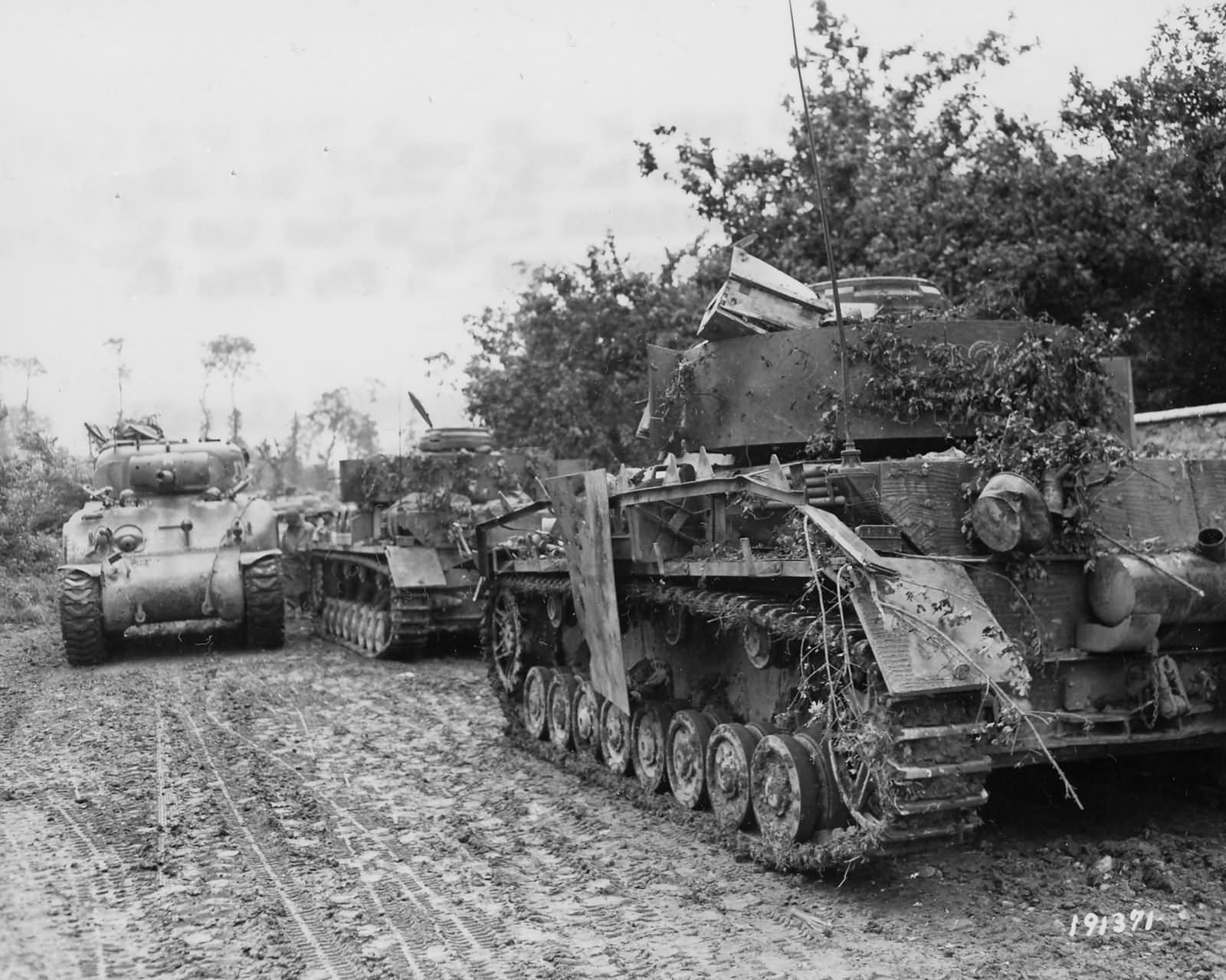 M4A1 Sherman of the 30th Infantry Division passes two German Panzer IV ...