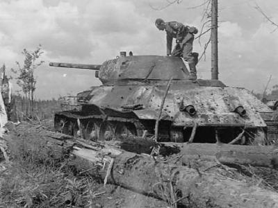 A german soldier stands on the top of a captured T-34/76 tank